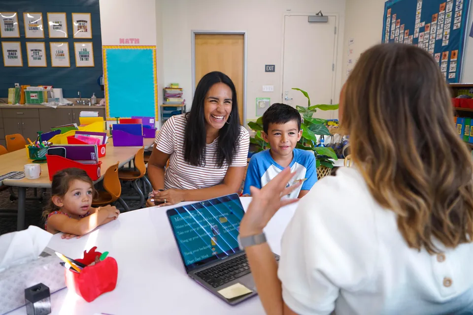 Docente compartiendo un momento con dos estudiantes en el aula